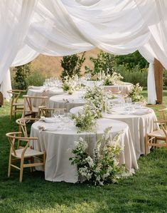 an outdoor table set up with white linens and greenery