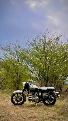 a motorcycle is parked in the grass near some trees