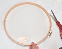 someone is making a wooden hoop with scissors