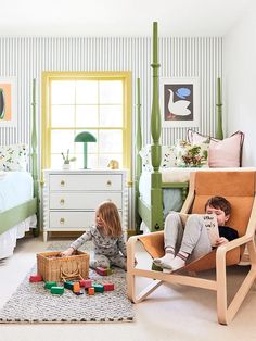 two children playing in a child's bedroom with green and white striped wallpaper