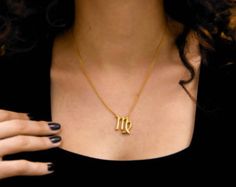 a woman wearing a gold necklace with the letter m on it's front and side