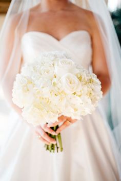 a bride holding a bouquet of white flowers