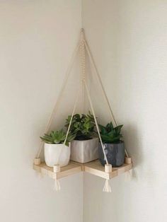 three potted plants are hanging from a shelf in the corner of a white room