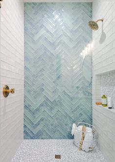 a bathroom with blue and white tiles on the wall, shower head, and tub