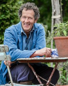 a man sitting at a table with a potted plant on it's side