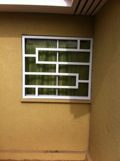 a toilet sitting under a window next to a tiled floor in front of a yellow wall