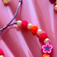 a close up of a necklace on a pink surface with pearls and beads around it