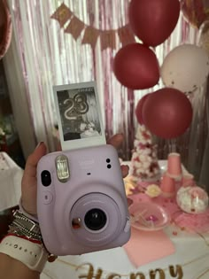 a person holding up a camera in front of a cake