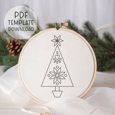 a cross stitch christmas tree is shown in front of a white background with pine cones