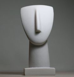 a white sculpture is standing on top of a wooden table and it looks like the head of a person