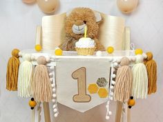 a teddy bear sitting at a table with a 1st birthday banner and cupcake on it