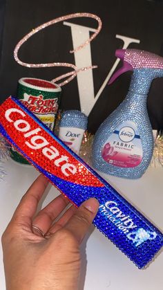 a hand holding a candy bar in front of some soda cans and other items on a table