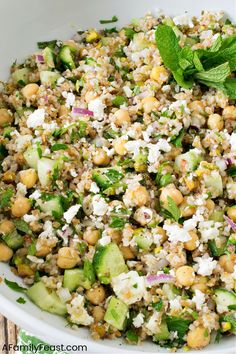 a salad with cucumber, chickpeas and feta cheese in a white bowl