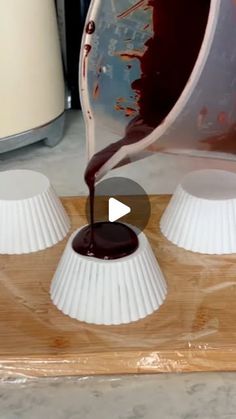 chocolate being poured into white paper cups on a cutting board