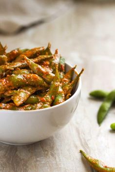 a white bowl filled with green beans on top of a table