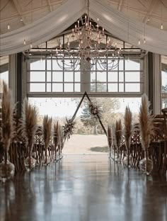 an indoor wedding venue with chandeliers and feathers on the aisle leading to it