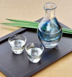 two glasses and a vase on a tray