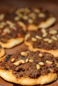 several small pizzas with meat and nuts on them