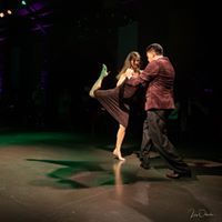 two people are dancing on stage in the dark