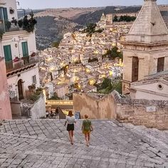 two people walking up some steps in front of a cityscape with buildings on the other side