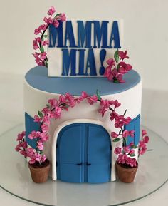 a blue and white cake with pink flowers on the top that says mamma mia