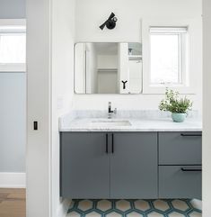 a bathroom with a sink, mirror and plant in the corner on the counter top