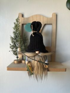 a doll with long hair and a knitted hat on top of a wooden chair