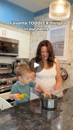 a woman standing next to a little boy in a kitchen