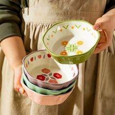 a woman holding several bowls in her hands