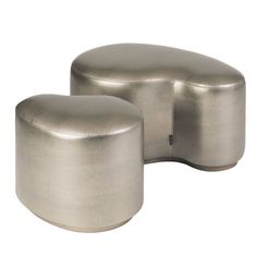 two silver stools sitting next to each other on a white background, one is shaped like an oval