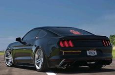 the rear end of a black mustang parked in a parking lot