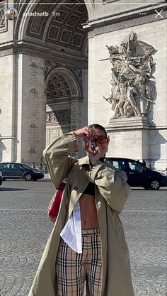 a man taking a photo with his cell phone in front of the arc de trioe