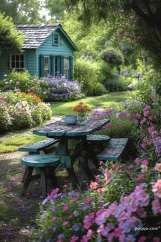 a picnic table in the middle of a garden with pink and purple flowers around it