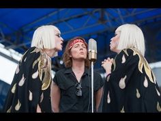 three women standing next to each other in front of a microphone on top of a stage