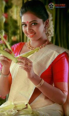 a woman in a red and white sari is holding up a piece of paper