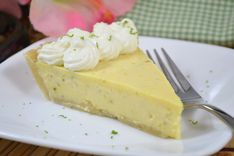 a piece of cheesecake on a white plate with a fork and flowers in the background