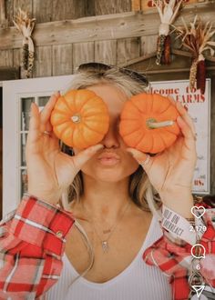 a woman holding two pumpkins in front of her eyes