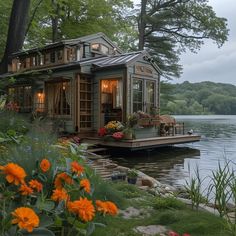 a small house sitting on top of a lake surrounded by trees and flowers in the foreground