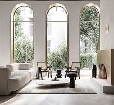 a living room filled with white furniture and large arched windowed windows next to a fireplace