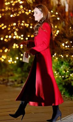 a woman in a red coat is walking down the street