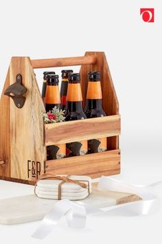 a wooden crate filled with bottles of beer next to a white ribbon and bottle opener