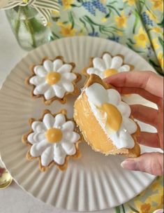 a hand holding a piece of food on top of a paper plate with flower decorations