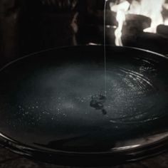 a black bowl sitting on top of a table with water pouring from the faucet