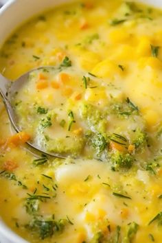 a white bowl filled with broccoli cheese soup and a spoon in the bowl