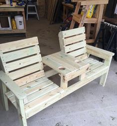 two wooden chairs sitting next to each other in a room filled with wood pallets