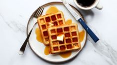 waffles with syrup and butter on a plate next to a cup of coffee