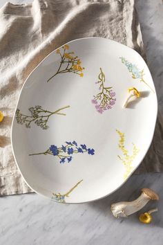 a white plate with yellow and blue flowers on it next to garlic cloves