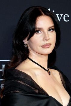 a close up of a person wearing a black dress and posing for the camera at an event