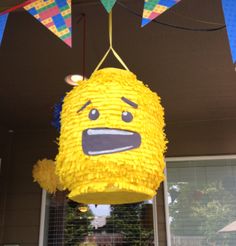 a yellow paper lantern with an angry face on it's side hanging from the ceiling