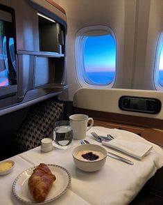 a table with food and drinks on it in front of an airplane's windows